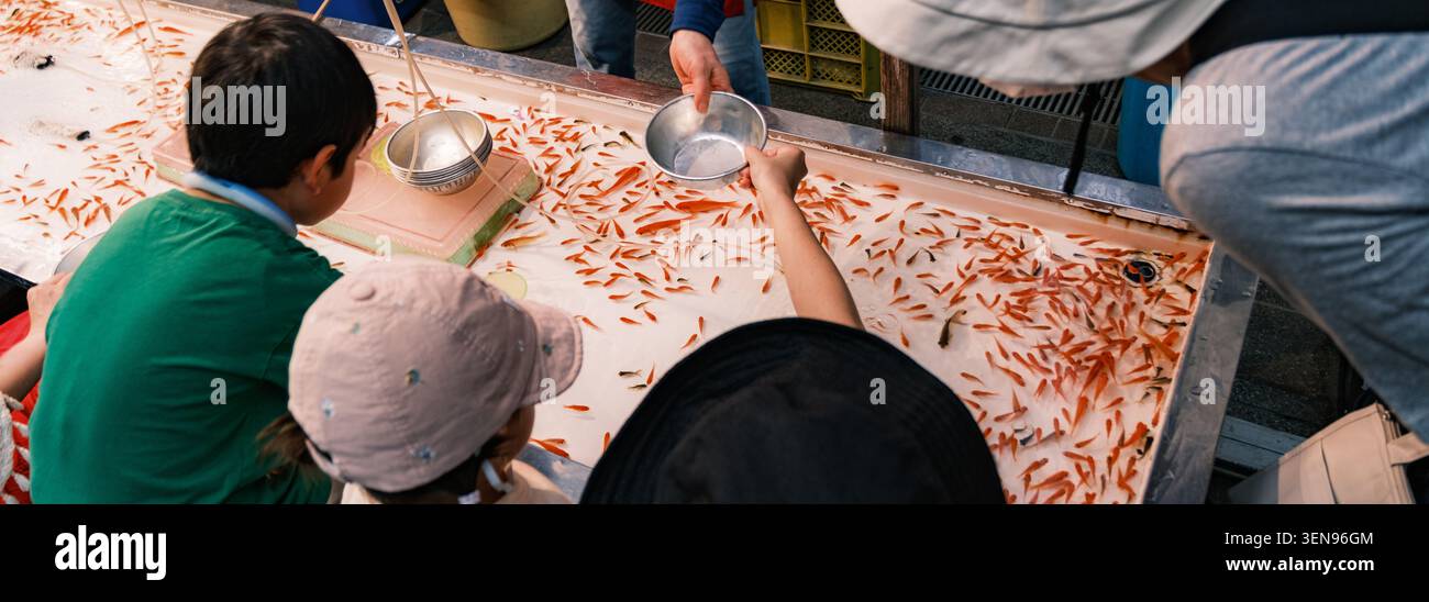 OSAKA - 24. JULI 2025: Kinder nehmen am traditionellen Goldfischschöpfer Kingyo-sukui auf dem lebhaften Tenjin Matsuri Festival Teil Stockfoto