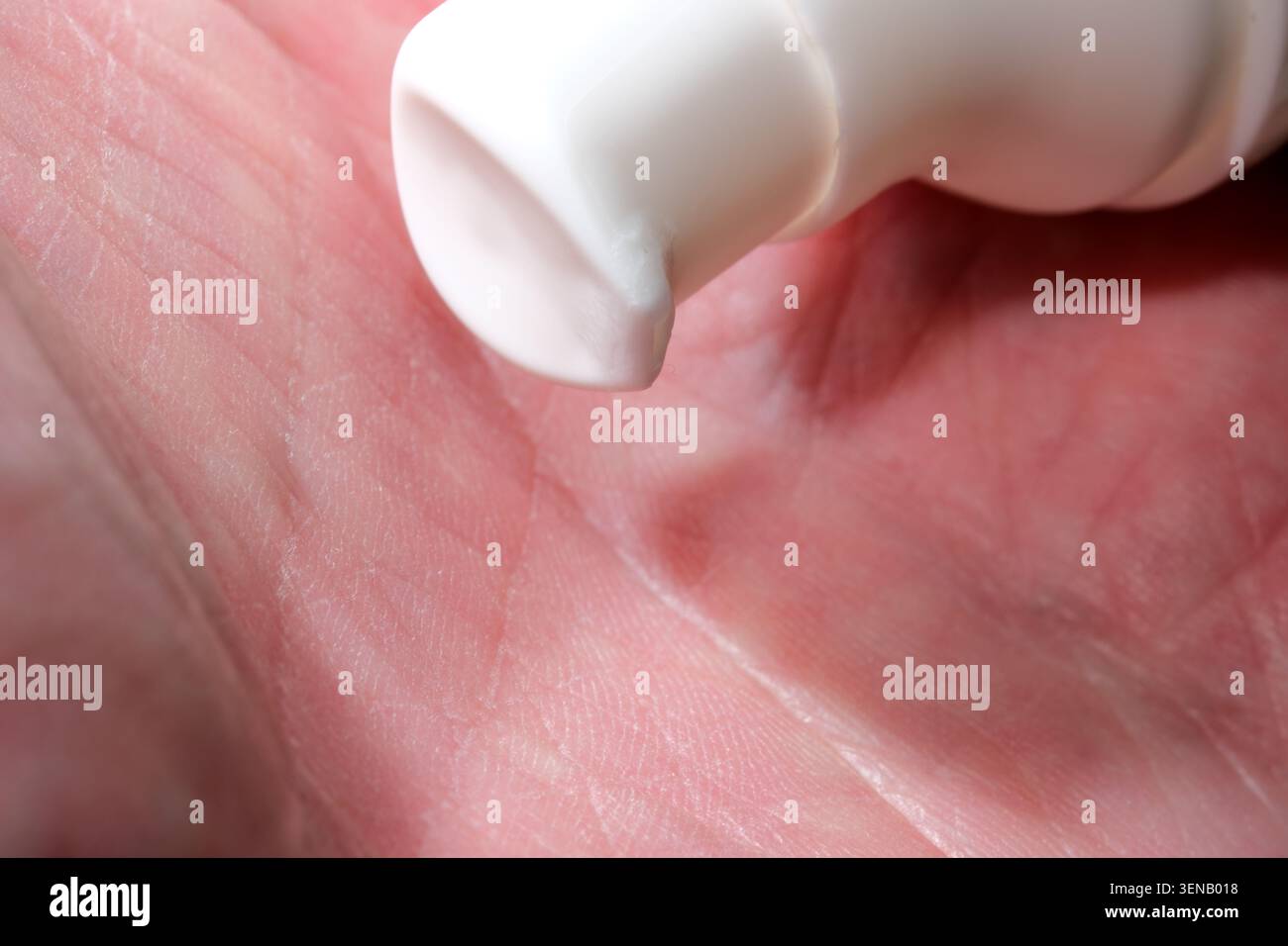 Eine Hand drückt sanft eine Tube zusammen, um eine weiche Creme aufzutragen, die die Pflege und Feuchtigkeit betont. Stockfoto