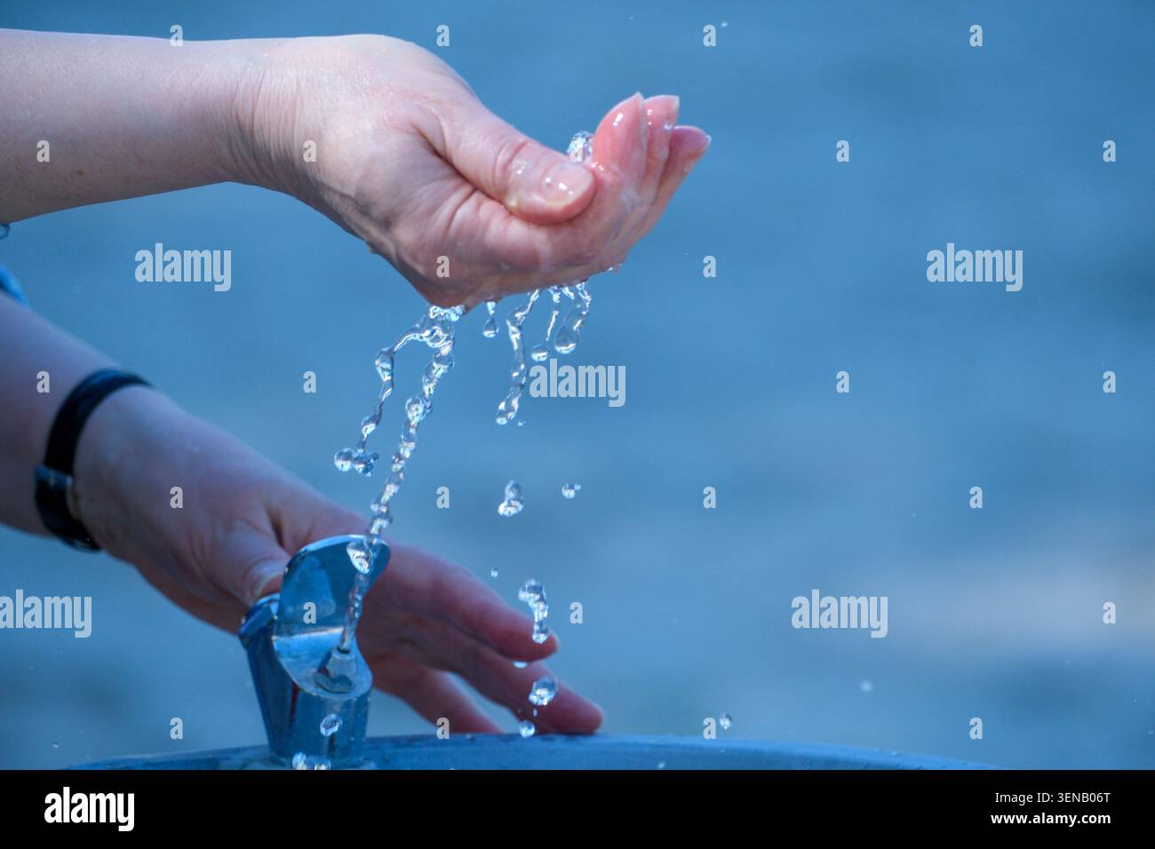 Das Wasser fließt anmutig aus den Händen und sorgt für einen beruhigenden Moment am See. Stockfoto
