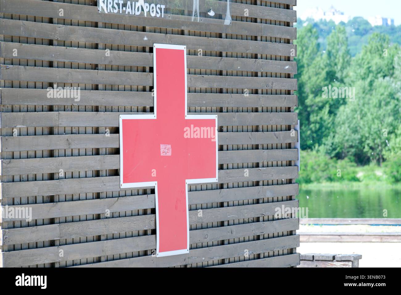 Hellrotes Kreuz signalisiert Sicherheit und Pflege in der Nähe des ruhigen Sees an einem sonnigen Tag. Stockfoto