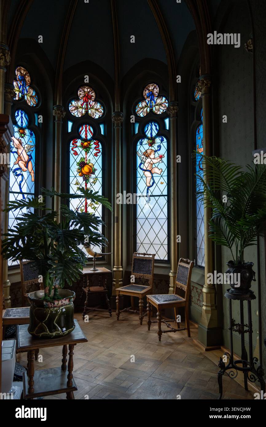 Königswinter, Deutschland - 22. Februar 25: Bucht-Fenster-Alkove mit Buntglaspaneelen, Stühlen und Pflanzen im Schloss Drachenburg, Königswinter, Nordrhein Stockfoto