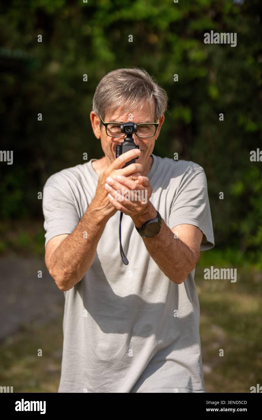 Senior Mann filmt ein Video mit einer Gimbal-Kamera, während er draußen Vloggen Stockfoto