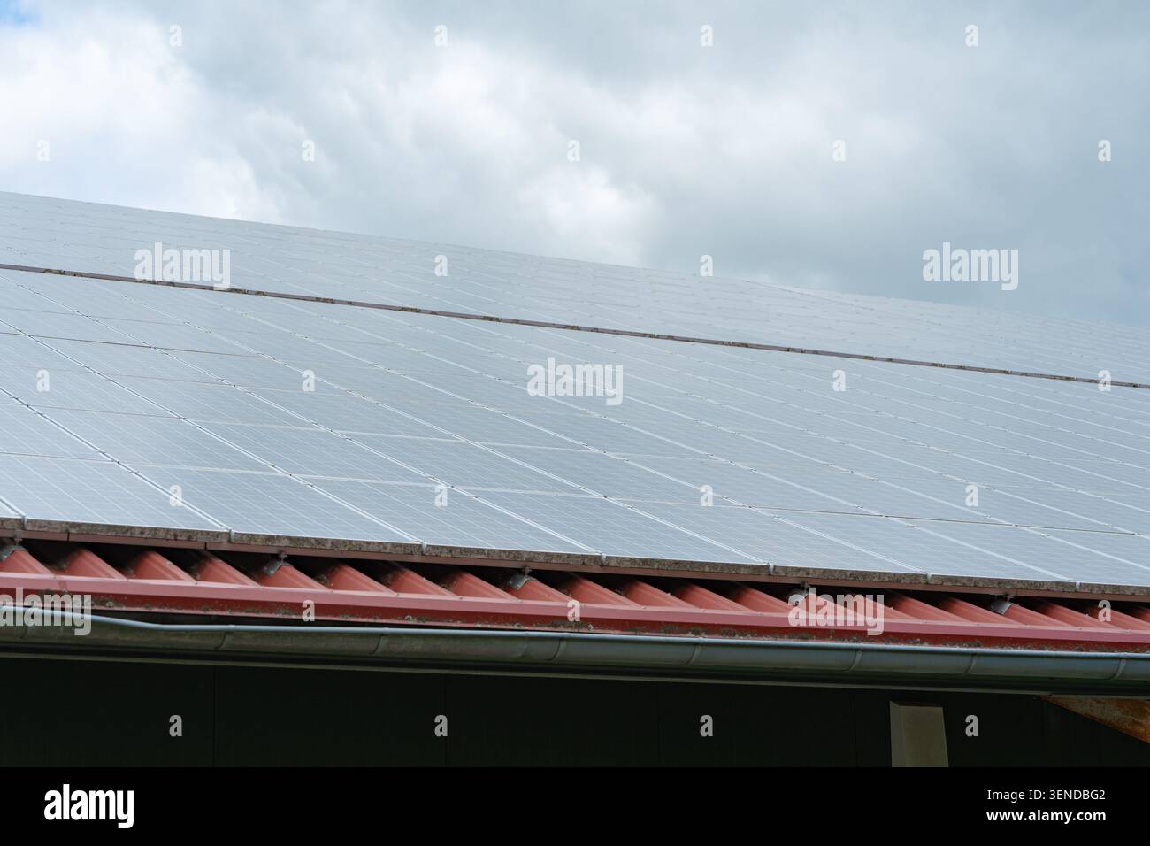 Niedrige Winkelperspektive von dunklen Solarpaneelen auf einem Wohnhausdach vor einem schönen bewölkten Himmel. Zeigt moderne Nachhaltigkeit Stockfoto