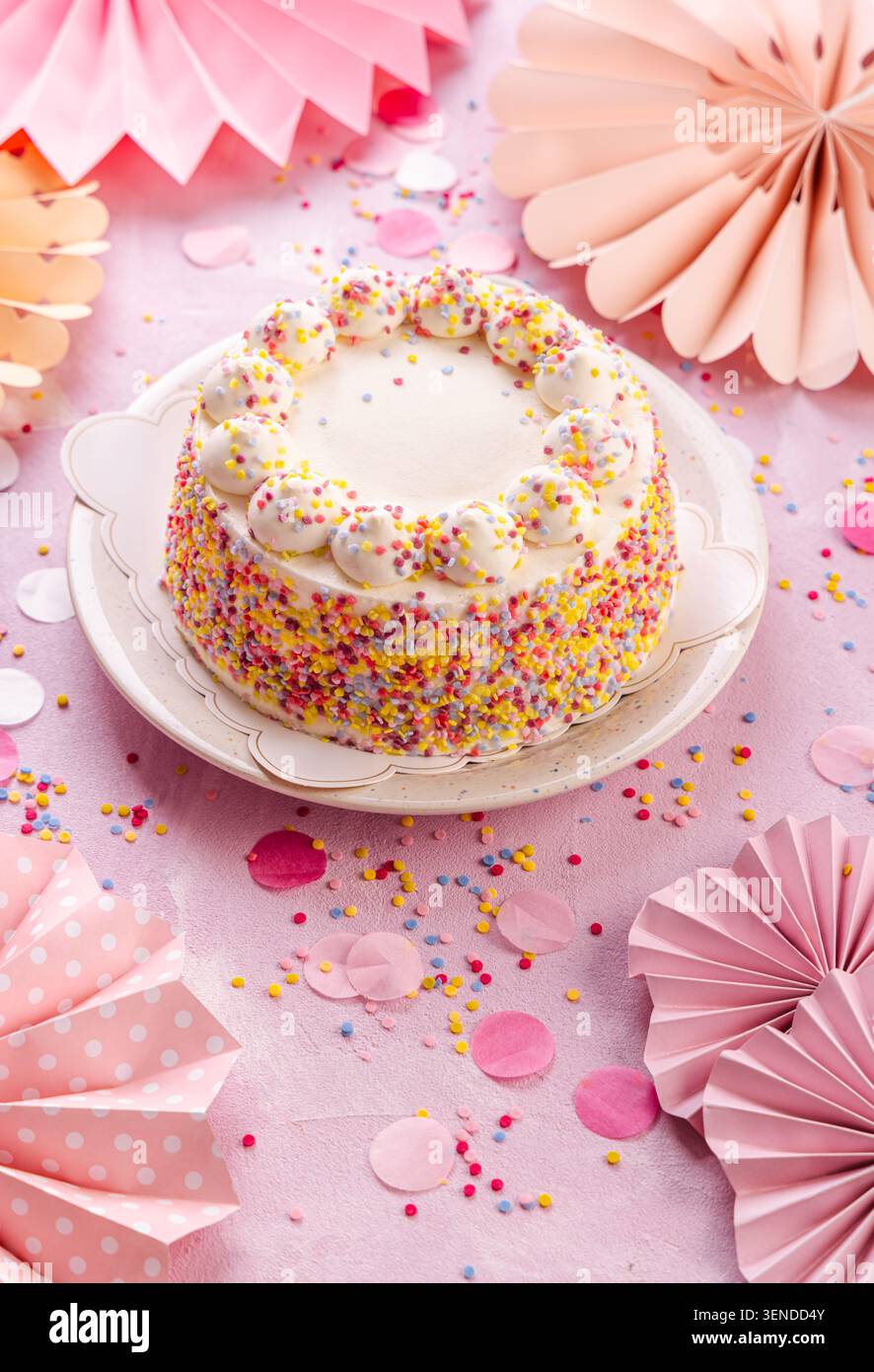Köstlicher Creme-Kuchen für Geburtstagsfeier mit rosa Papierdekorationen Stockfoto