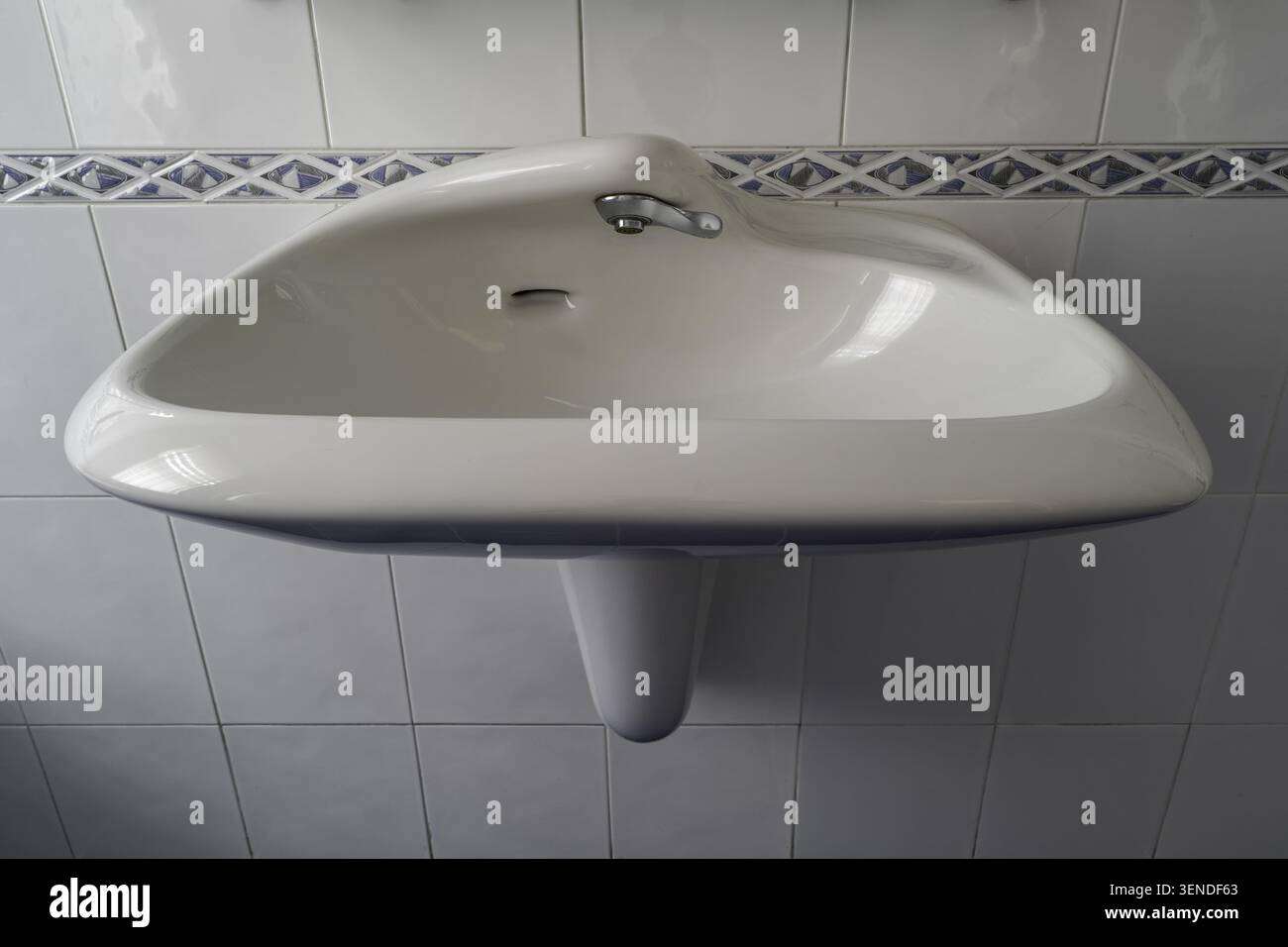 Weißes keramikbeschichtetes Wand-Waschbecken mit Chrom-Wasserhahn, geflieste Wandinnenseite Nahaufnahme Stockfoto