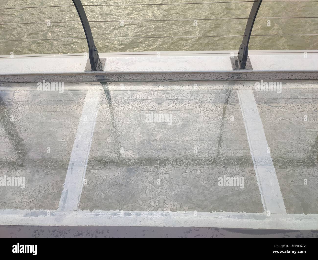 Ein hochgezogenes architektonisches Detail aus transparenten Glasbodenpaneelen, die nach einem Sturm mit frischen Regentropfen bedeckt sind. Die minimalistische Komposition hebt St.1 hervor - Smartphone-aufgenommenes Stockfoto