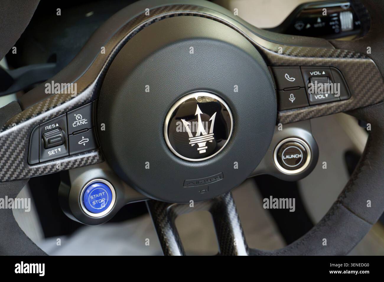 Nahaufnahme eines modernen Maserati Sportwagenlenkrads mit Karbonfaserverkleidung und dem legendären Trident-Logo Stockfoto