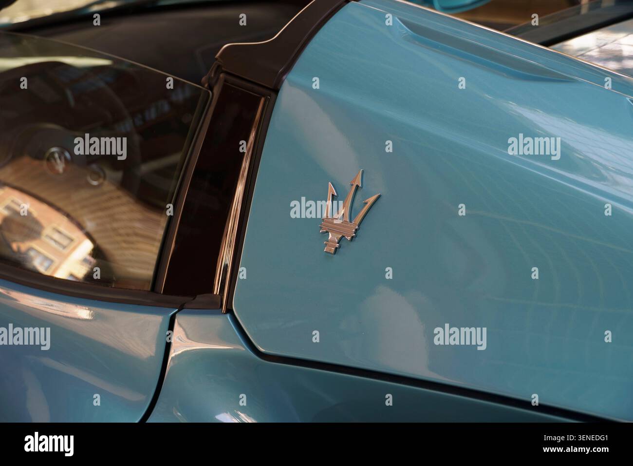Nahaufnahme des verchromten Trident-Emblems an einem modernen hellblauen Maserati-Sportwagen-Cabrio Stockfoto