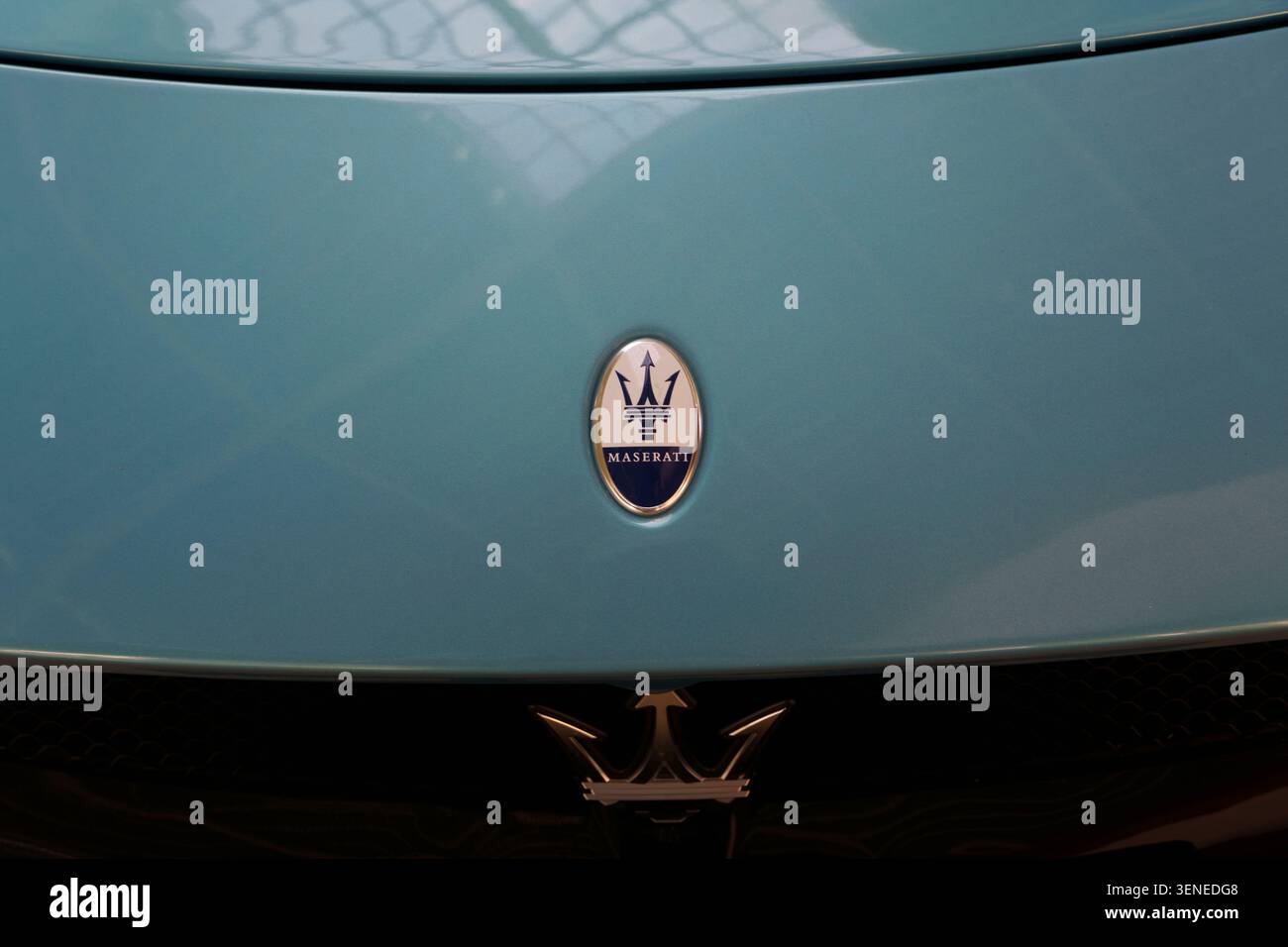 Nahaufnahme des Maserati Trident Emblems auf der vorderen Motorhaube eines blauen Luxussportwagens Stockfoto