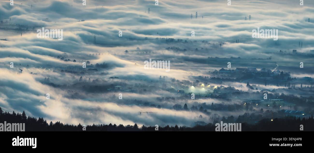 Luftpanorama mit atmosphärischem Nebel, der eine malerische Szene über einer Stadt bei Sonnenaufgang schafft Stockfoto
