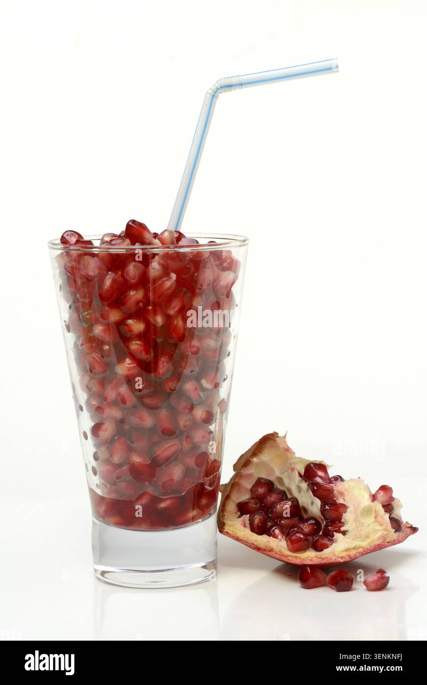 Granatapfelsamen in Glas und Stroh, halbierter Granatapfel Stockfoto