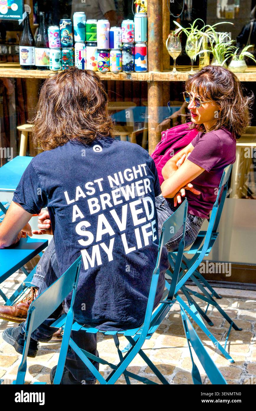 Junges Paar im Café mit einem Mann im T-Shirt mit der Humorbotschaft „Last Night A Brewer hat mein Leben gerettet“ - Tours, Indre-et-Loire (37), Frankreich. Stockfoto