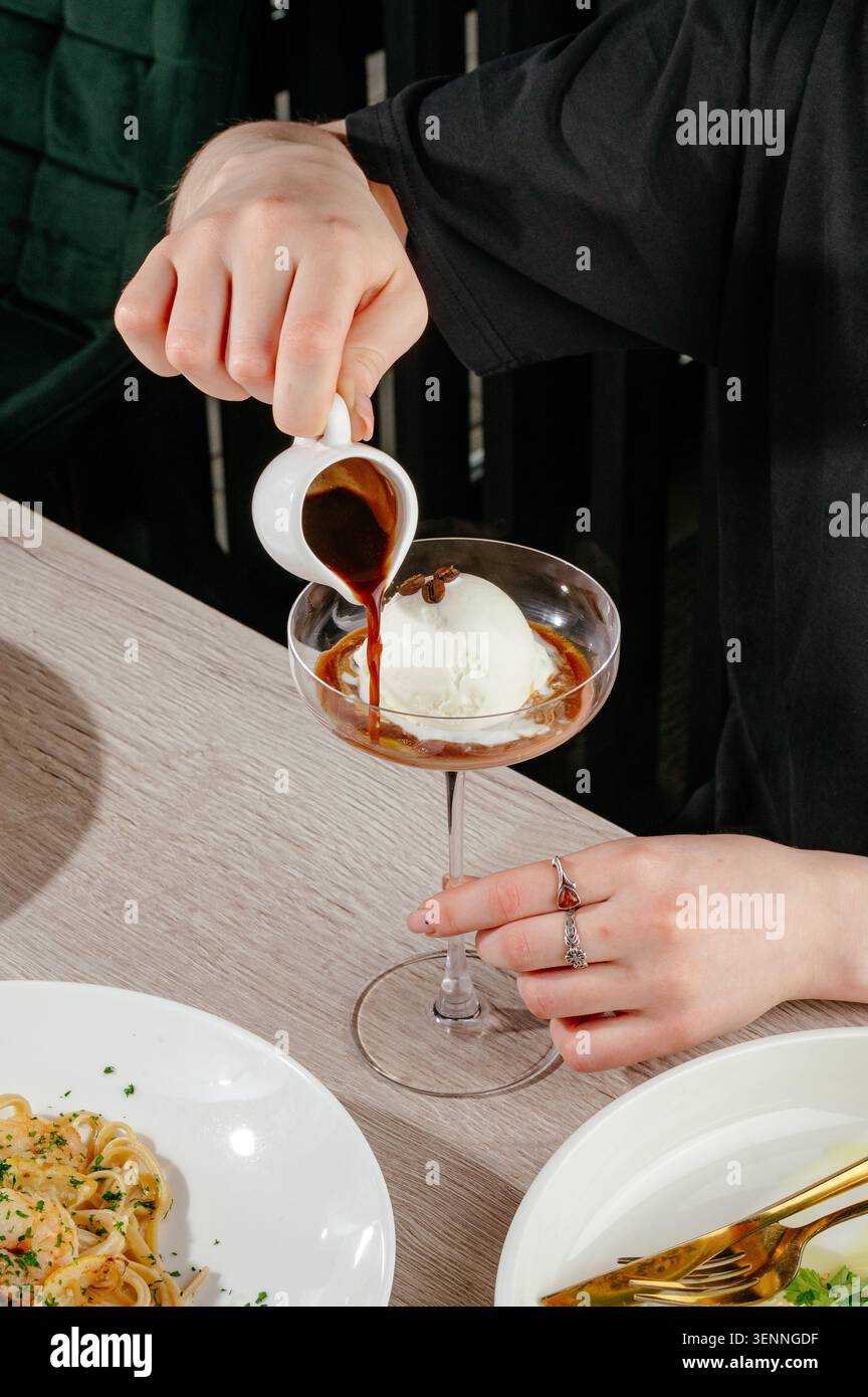Ein Mann, der Espresso über eine Schaufel Eis gießt Stockfoto