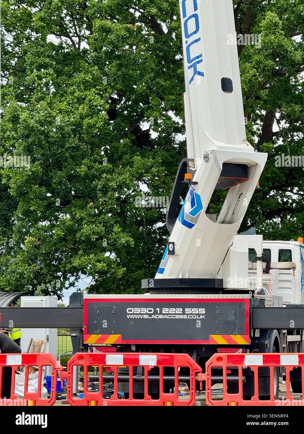 Kesgrave, Suffolk - 12. Juni 2026 : Kran und Plattform mit Männern, die an einem Netzmast im Sportzentrum arbeiten. - Smartphone-aufgenommenes Stockfoto