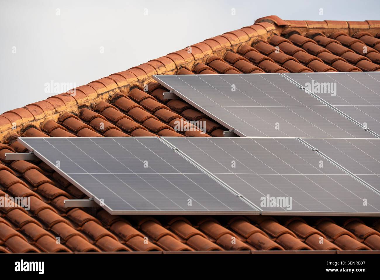 Nahaufnahme moderner Photovoltaik-Solarpaneele auf einem traditionellen Dach mit Terrakotta-Ton-Fliesen. Stockfoto