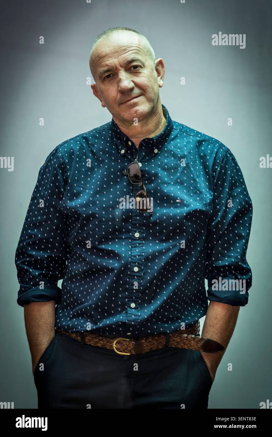Phillipe Claudel posiert mit den Händen in den Taschen. Er trägt ein gepunktetes Hemd. Der Hintergrund ist einfach und schlicht. Stockfoto