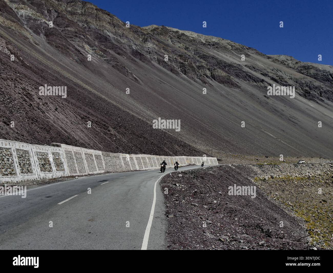 Malerische Berglandschaft mit Motorradfahrern in der Ferne auf der Straße, in Ladakh, Nordindien. Beliebtes Reiseziel für Roadtrips im Sommer Stockfoto