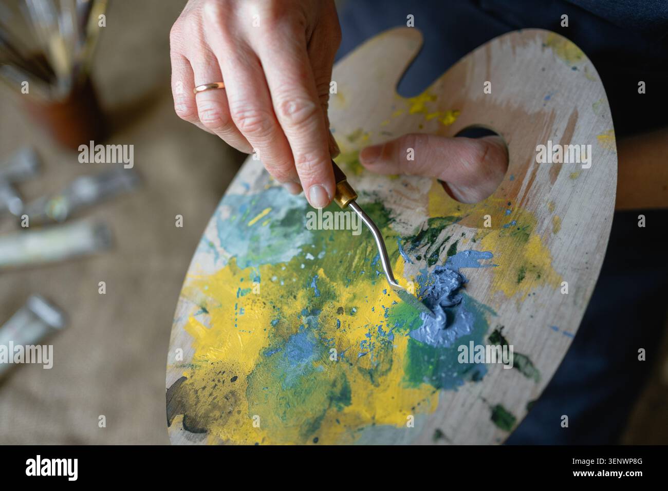 Nahaufnahme einer Holzpalette mit bunten Farben in Künstlerhänden. Malprozess, Kreativität, Kunst, Inspiration und künstlerisches Arbeitskonzept Stockfoto