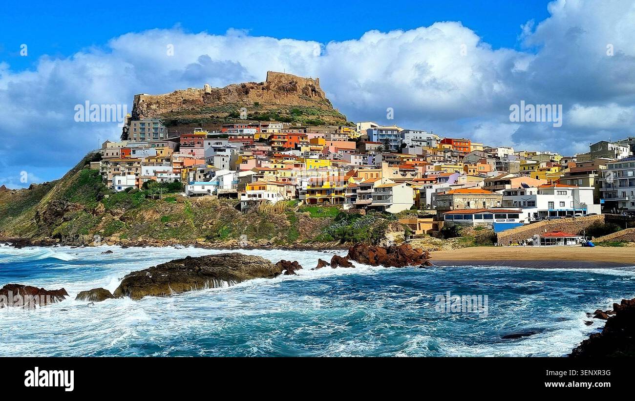 Blick auf das türkisfarbene Meer mit Klippen und die farbenfrohe Stadt Castelsardo, Sardinien, Italien Stockfoto