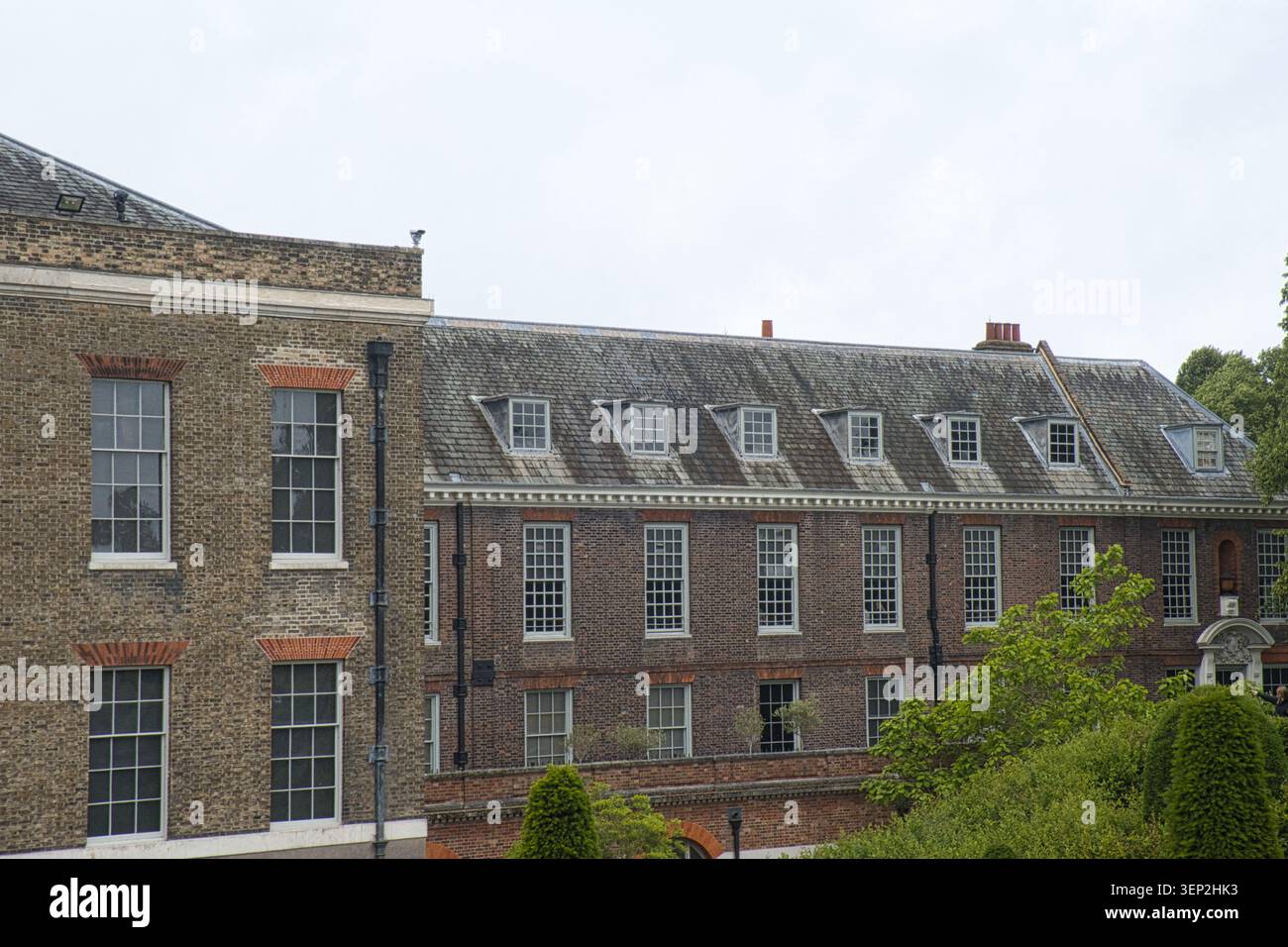 Außenansicht des Kensington Palace, London, mit der historischen Backsteinfassade, Schiebefenstern und Dachbalken auf einem schiefergedeckten Mansardendach. Stockfoto