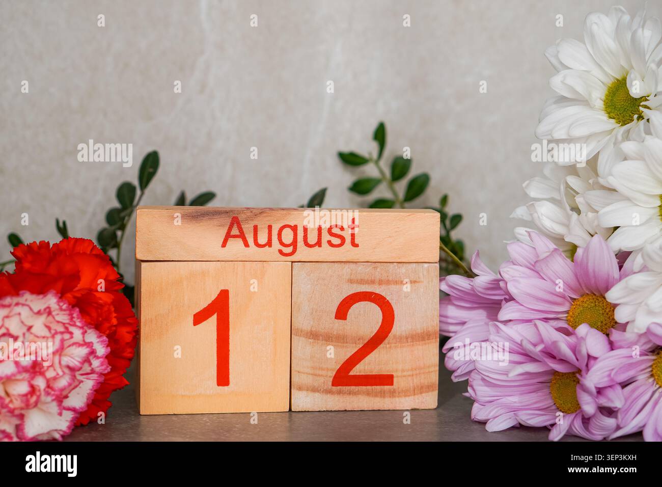 August. Holzkalender mit frischen Blumen. Kopierbereich. Stockfoto