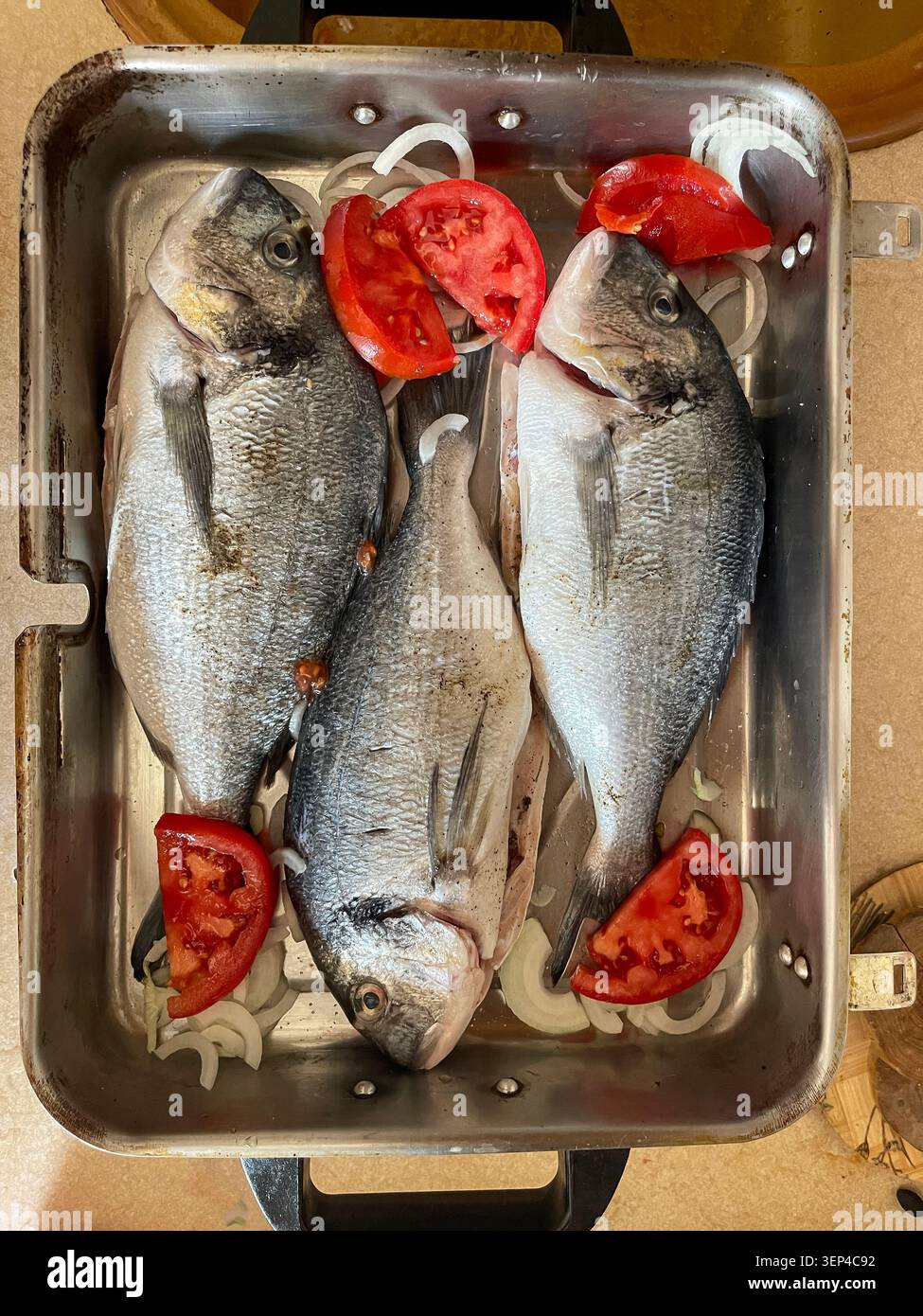 Frischer ganzer Fisch, der mit natürlichen Zutaten zum Kochen vorbereitet wurde, bevor er gebacken wird. - Smartphone-aufgenommenes Stockfoto