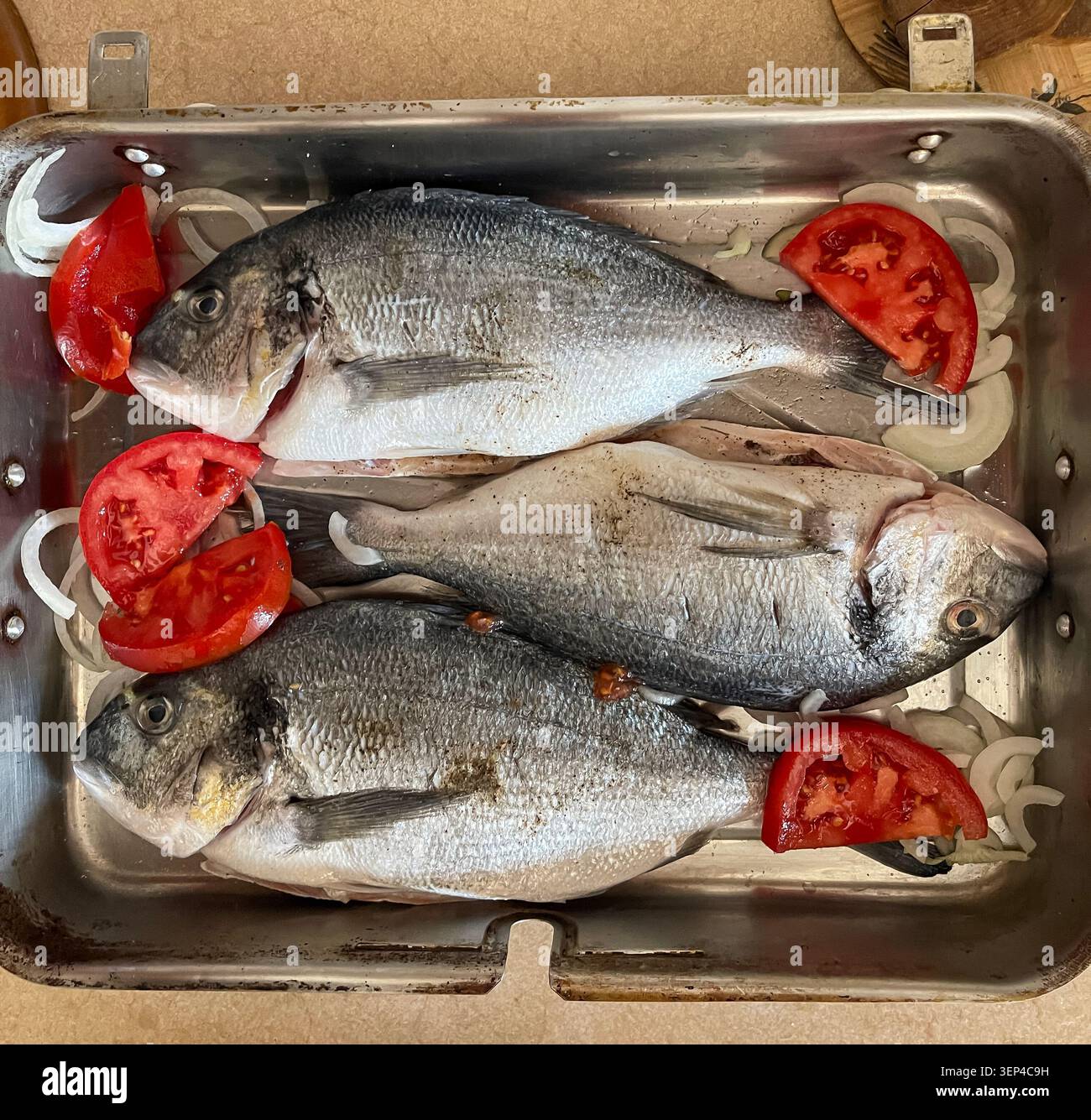 Frischer ganzer Fisch, der mit natürlichen Zutaten zum Kochen vorbereitet wurde, bevor er gebacken wird. - Smartphone-aufgenommenes Stockfoto