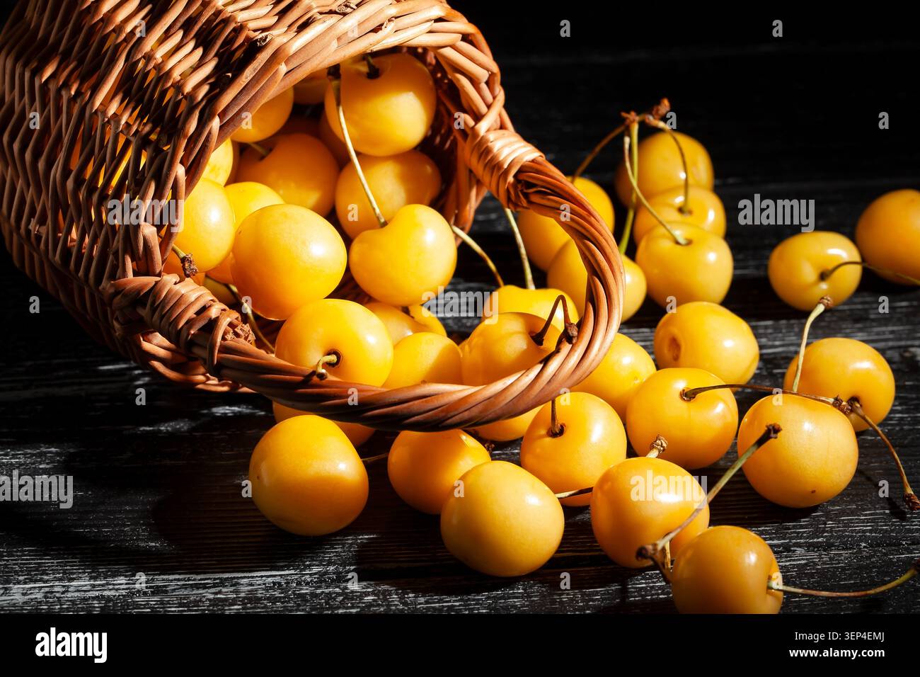 Gelber Kirschkorb auf schwarzem Holzhintergrund Stockfoto