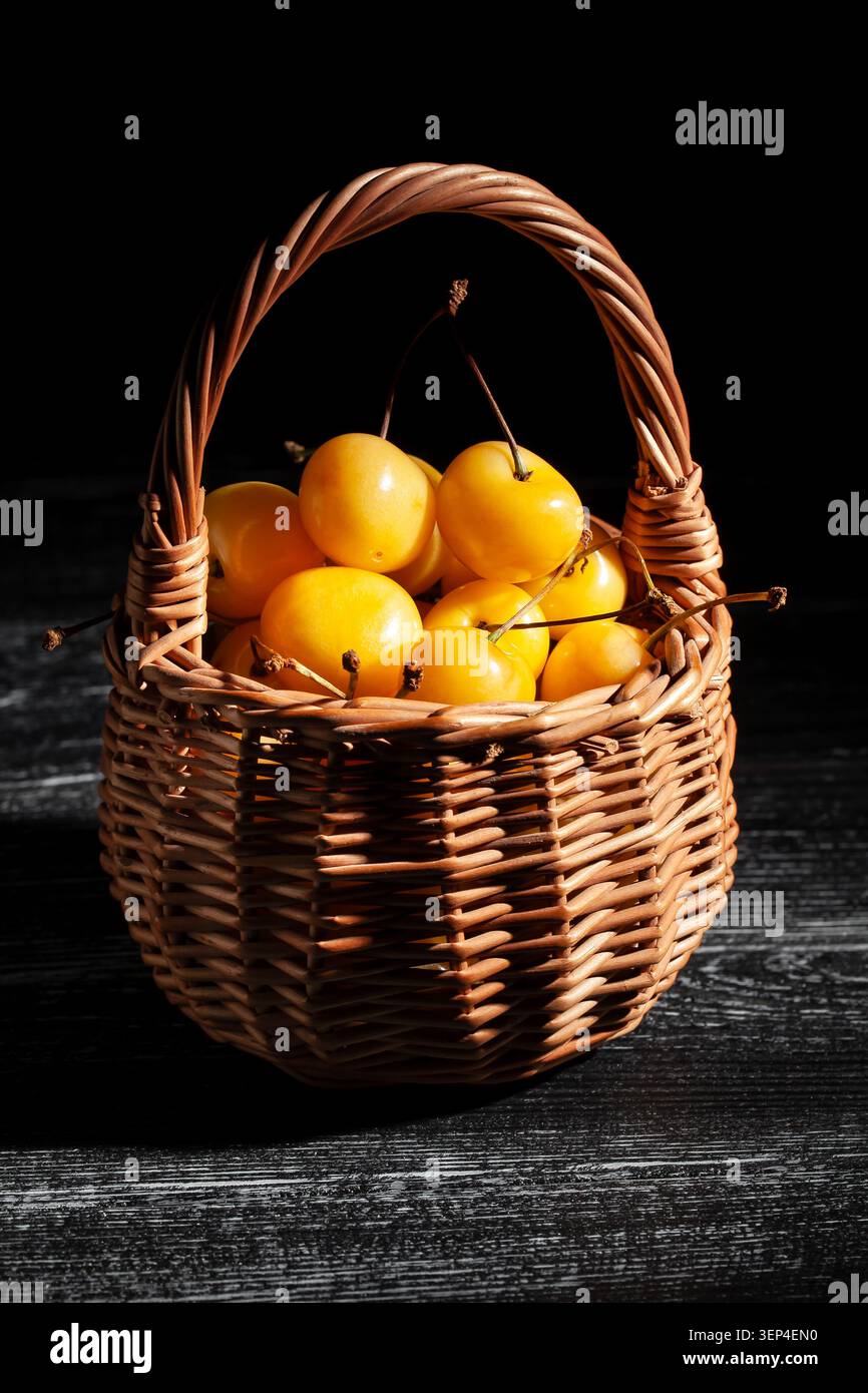 Gelber Kirschkorb auf schwarzem Holzhintergrund Stockfoto