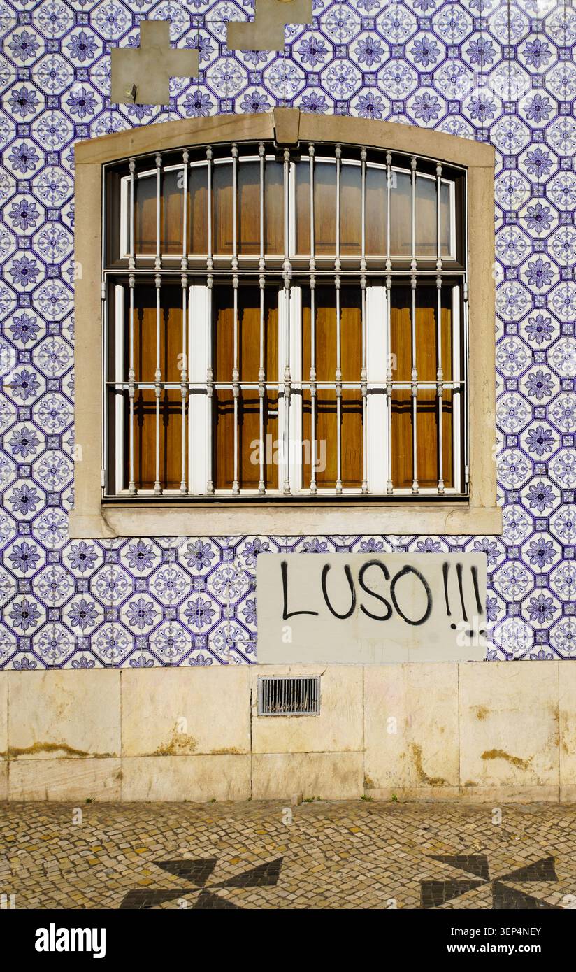 Azulejo-verkleidete Fassade mit verschlossenem Fenster und „LUSO!!!“-Graffiti-Tag, Portugal Stockfoto