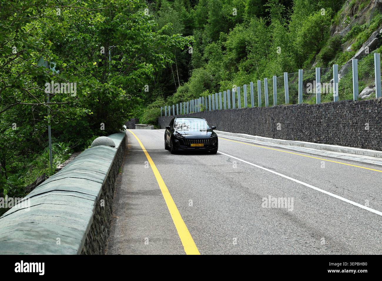 Schwarzer SUV, der auf dem Mountain Highway mit Schutzbarriere fährt Stockfoto