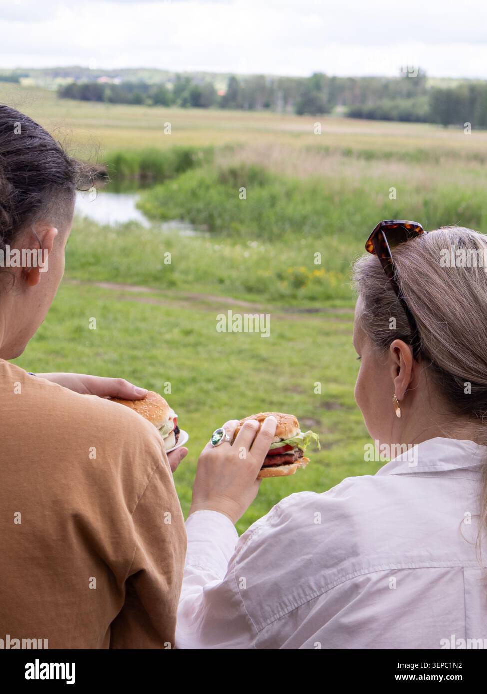 Ein Paar mittleren Alters genießt ein Picknick-Essen und blickt auf die offene Landschaft. Gemeinsames Abendessen im Freien, Familienverbundenheit und Entspannung Stockfoto