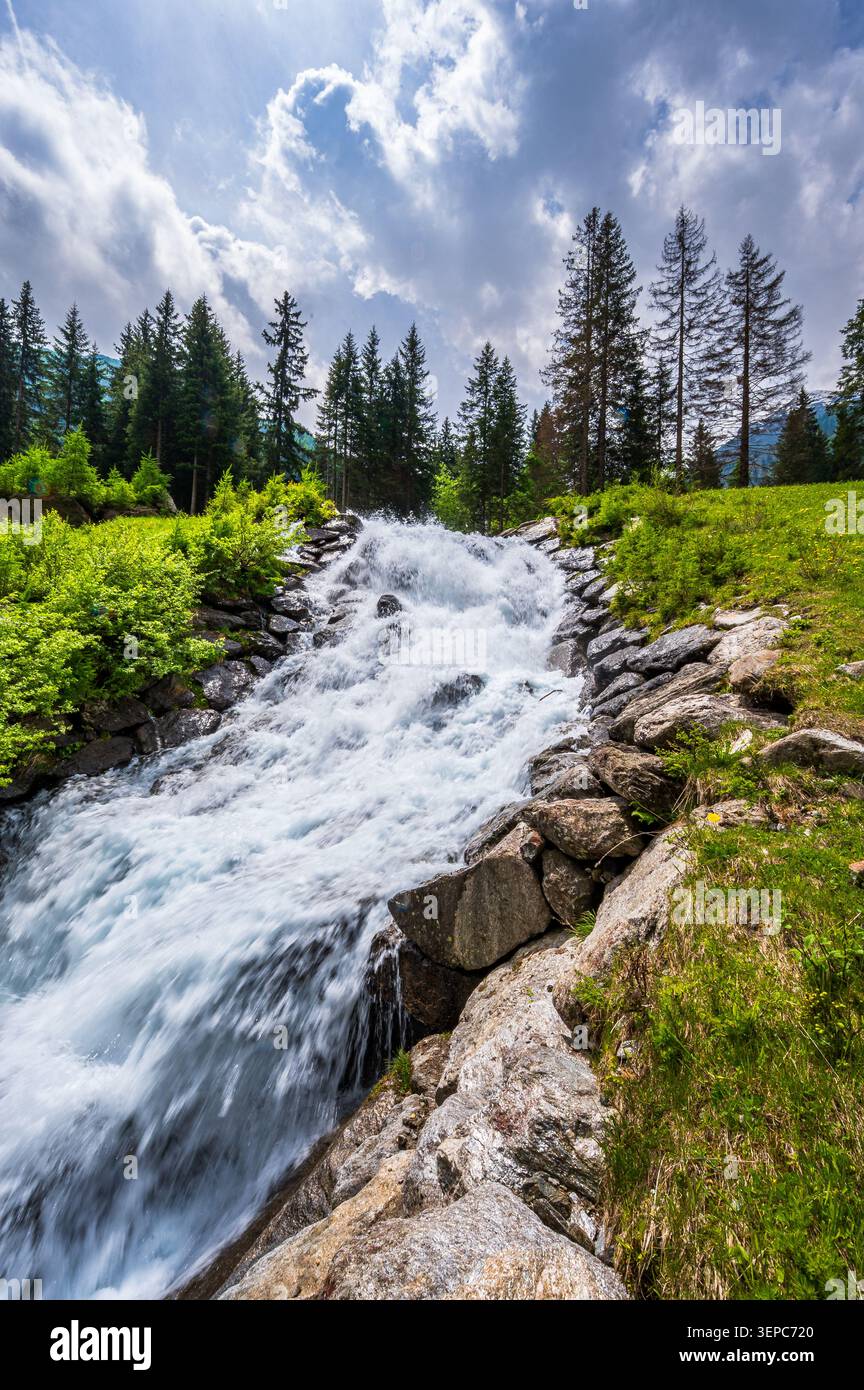 Dynamischer alpiner Wasserfall, der bei hellem Tageslicht über Felsen bei Pfelders in Südtirol, Italien, rauscht. Der mächtige Strom fließt durch einen felsigen Kanal Stockfoto