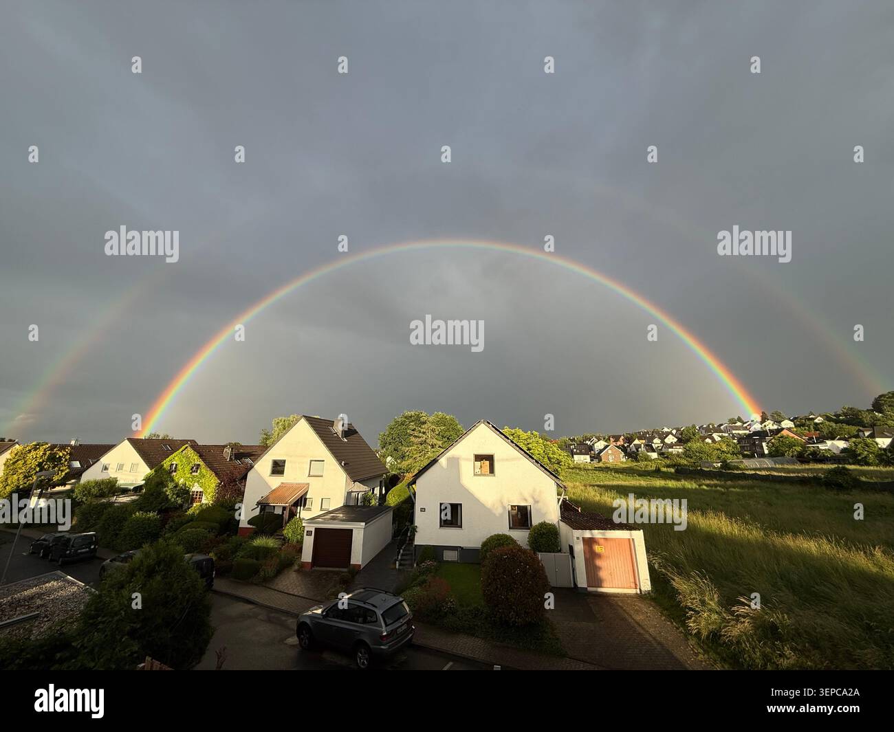 Spektakulärer doppelter Regenbogen bei Sonnenuntergang über der Villade Landschaft Stockfoto