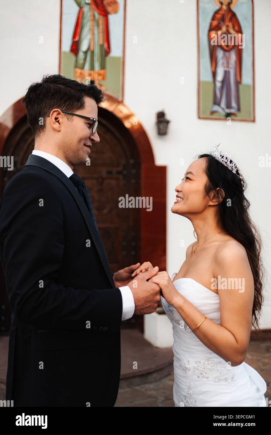 Braut und Bräutigam halten Hände und lächeln an ihrem Hochzeitstag Stockfoto