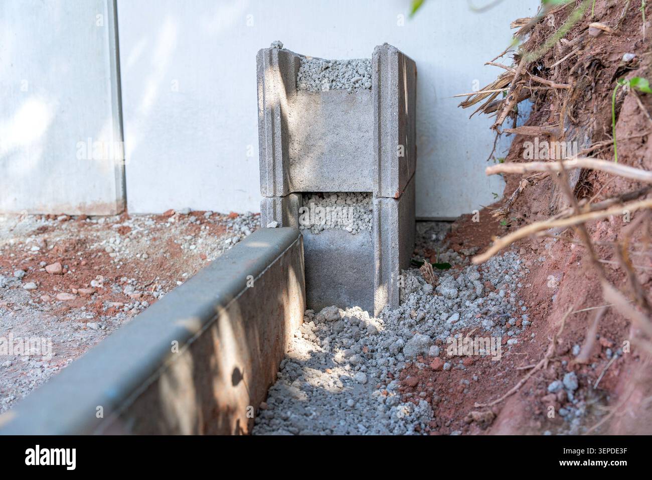 Ein neu installiertes Betonabfluss- oder Stützwandelement, das auf einer Baustelle im Hinterhof mit gebrochenem Kies gefüllt ist. Zeigt die Wasserwirtschaft Stockfoto