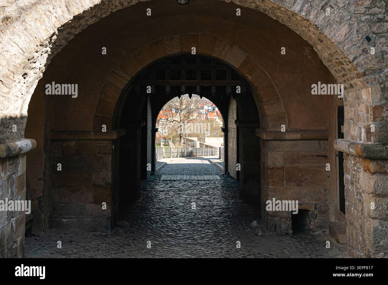 Erfurt, Deutschland - 27. März 2026. Steinbogengang in der Petersberger Zitadelle mit Kopfsteinpflaster, alten Festungsmauern, hölzernen Tordetails, A Stockfoto