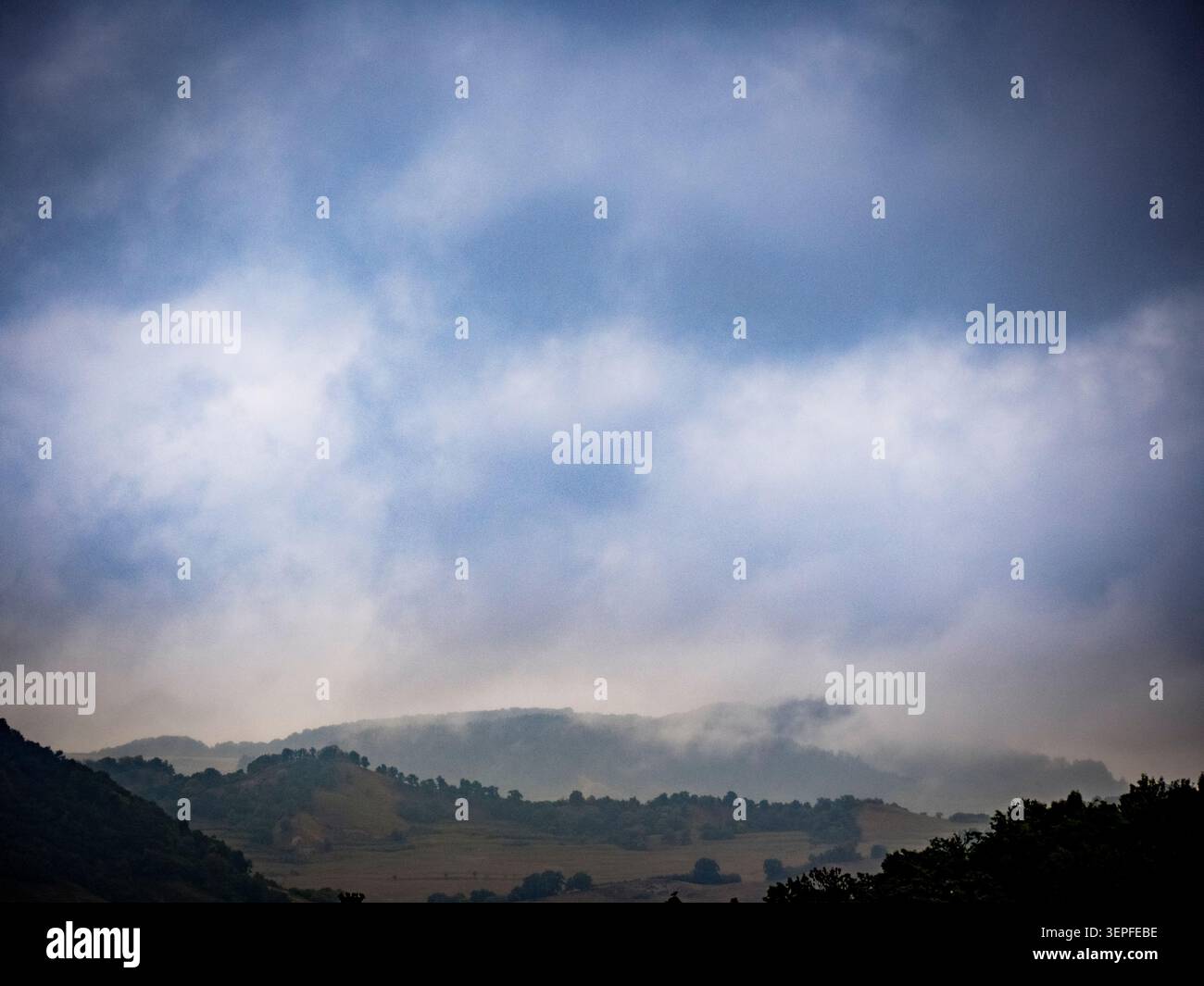 Dramatische stimmungsvolle Landschaft mit nebeligen bewaldeten Hügeln und stürmischem Himmel in Siebenbürgen, Rumänien. Die Kulisse von Bram Stokers Dracula. Stockfoto