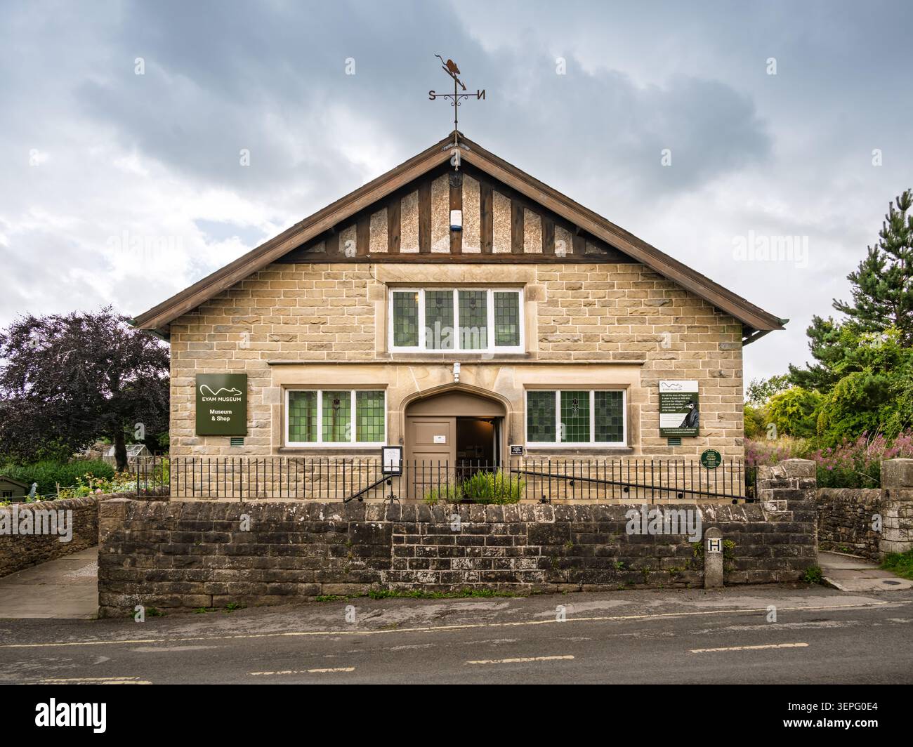 Das Eyam Museum befindet sich auf der Vorderseite des Grausteingebäudes mit seiner unverwechselbaren Giebeldachlinie und einer Pestrattenwetterfahne an der Hawkhill Road Stockfoto