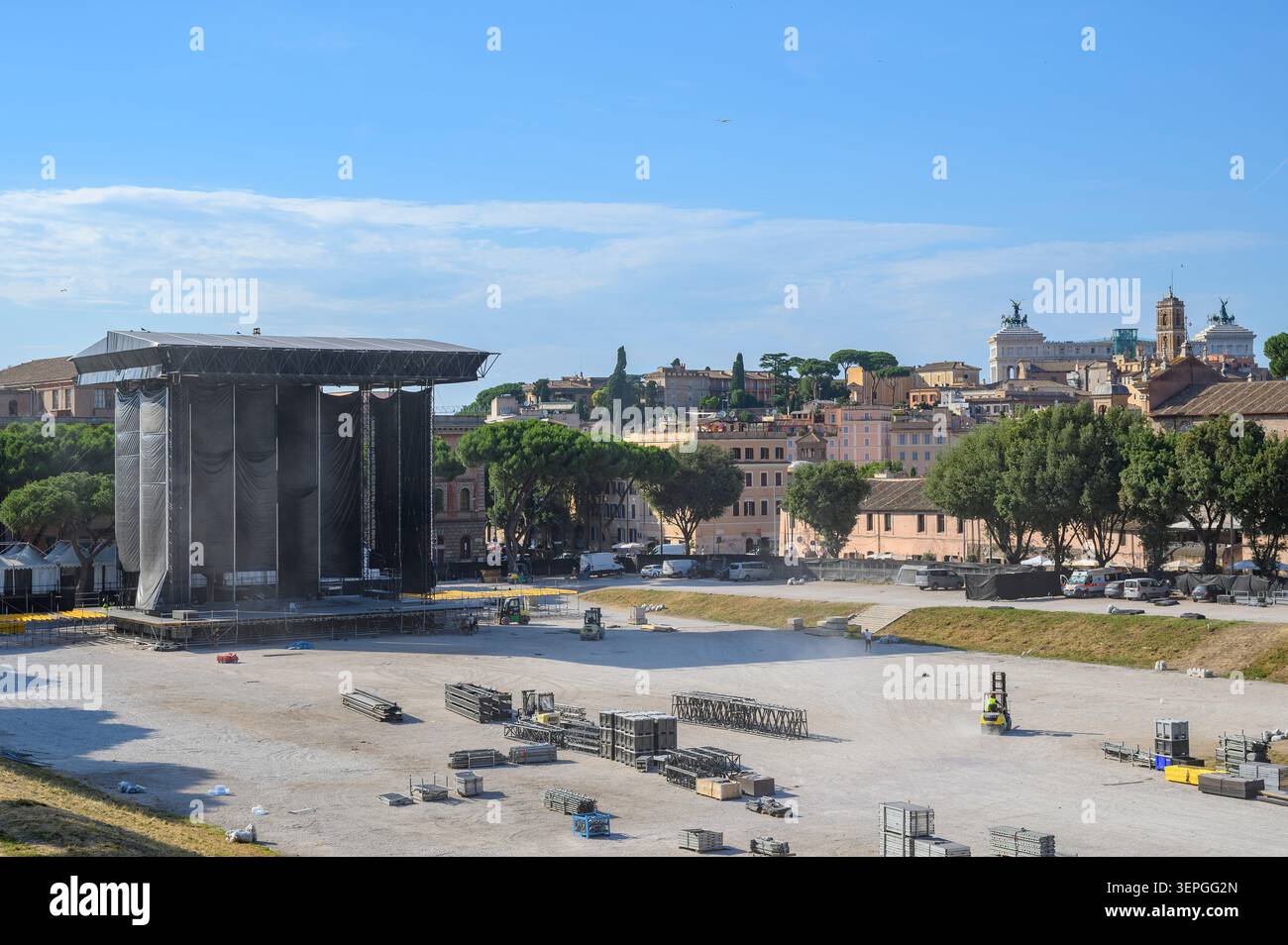 Der Bau und die Aufstellung einer massiven Konzertbühne im Circus Maximus in Rom, Italien, mit der historischen Stadtlandschaft im Hintergrund Stockfoto