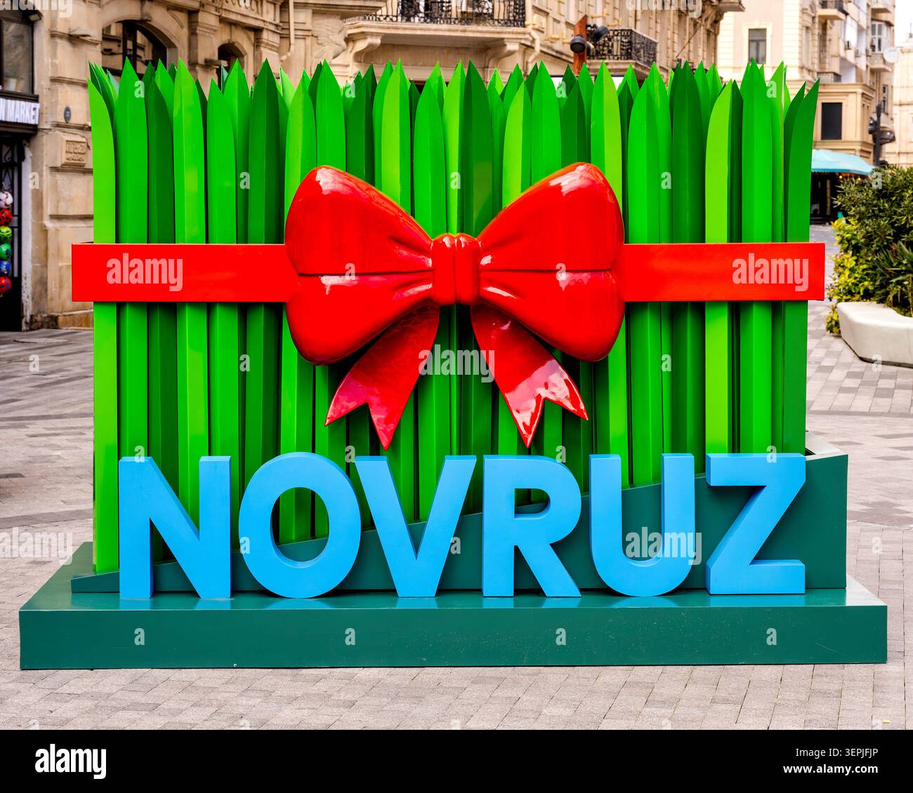 Große dekorative Installation von Semeni-Weizengras mit roter Schleife und Novruz-Schriftzug auf der Rasul Rza Street. Baku, Aserbaidschan. Stockfoto