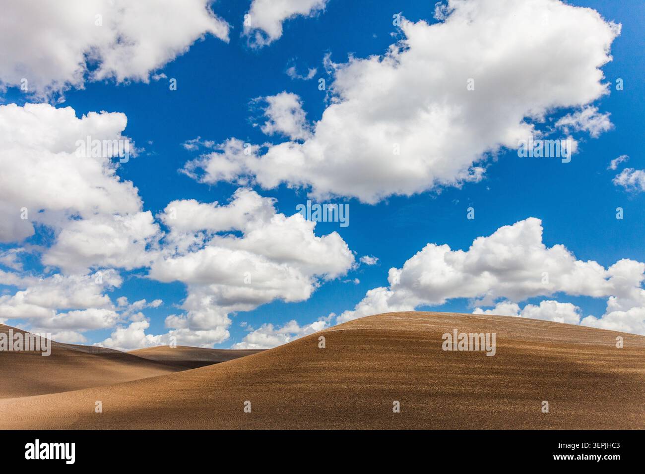 Blauer Himmel und Wolken über braunen Hügeln Stockfoto