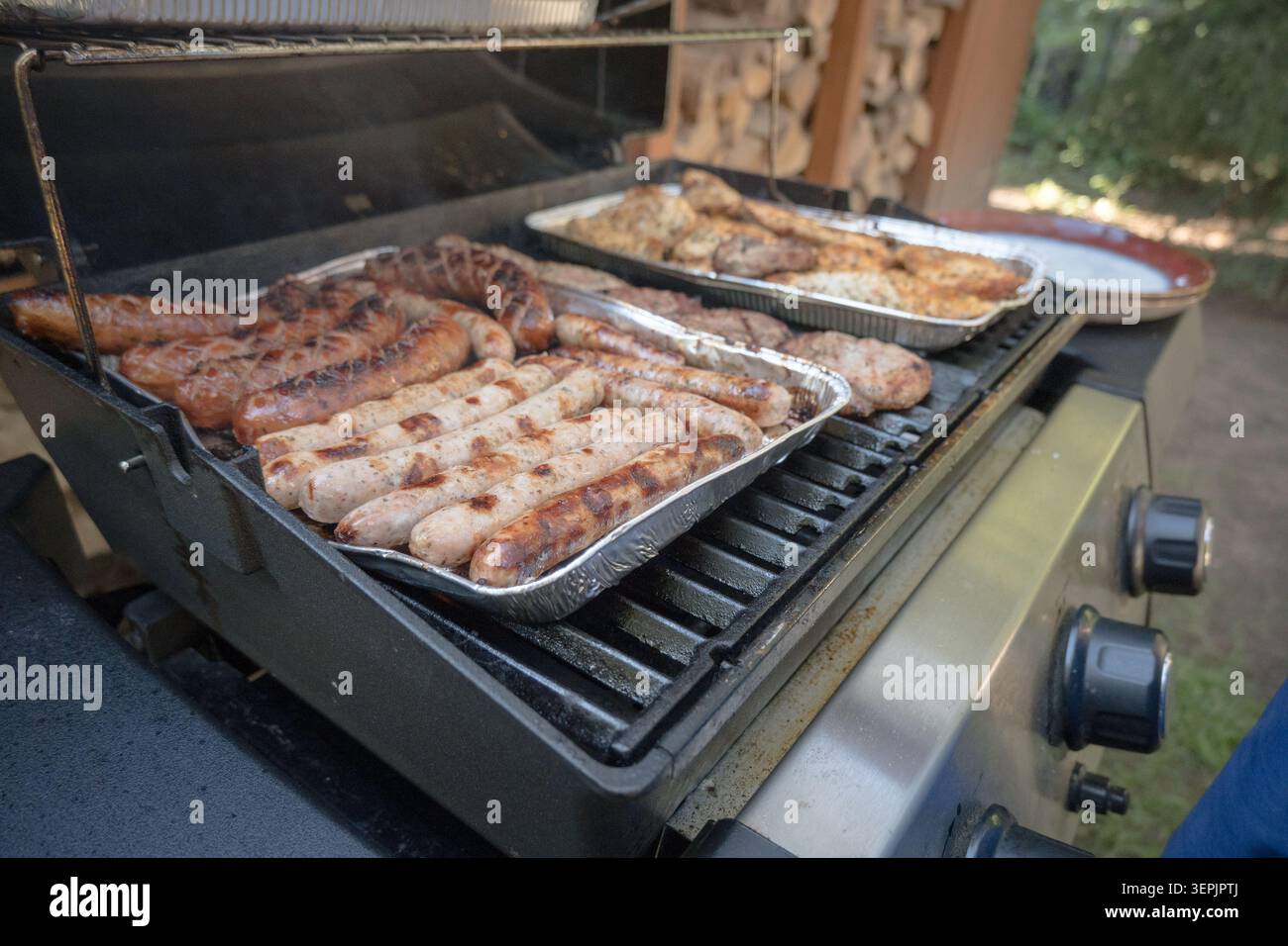 Fleisch, Würstchen, Gemüse auf einem Gasgrill grillen. Stockfoto