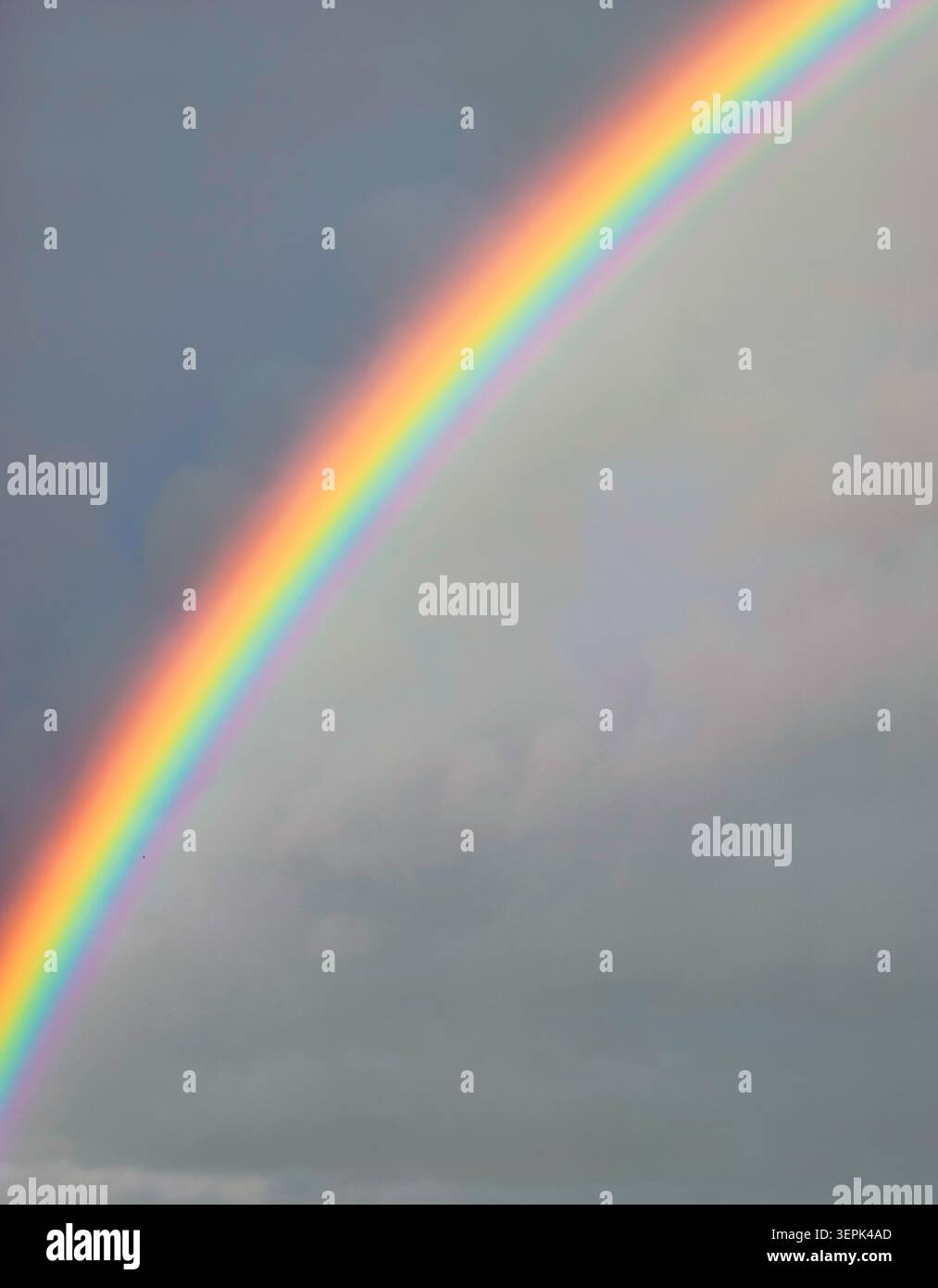 Regenbogen gegen dramatische Nachregenwolken, die Hoffnung, Erneuerung und Positivität symbolisieren. Naturhintergrund für Wellness-Branding, inspirierende Projekte Stockfoto