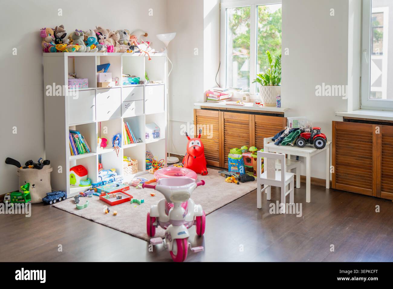 Das Innere des unordentlichen Kinderzimmers ist mit einem großen Ablagefach voll mit Kuscheltieren, Büchern und verstreuten Lernspielzeugen auf einem Teppich ausgestattet Stockfoto