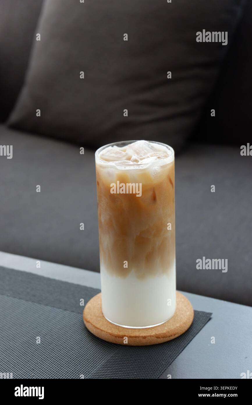 Ein Glas Eiskaffee mit Milch in einem gemütlichen Wohnzimmer. Eiskaffee Stockfoto