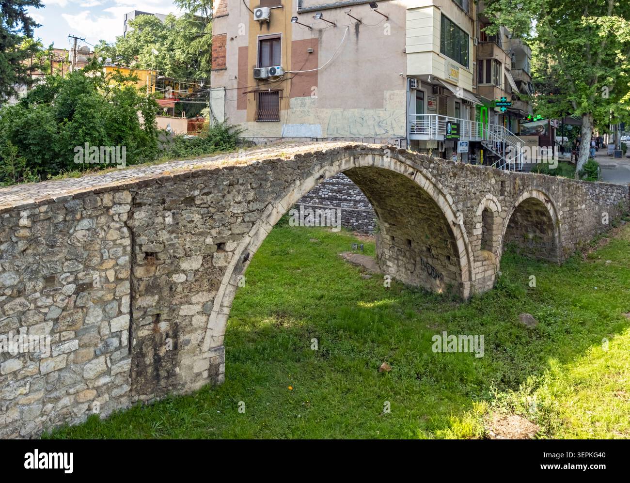 Tanners' Bridge - historische Steinbrücke aus der osmanischen Zeit - umgeben von grünem Gras und Stadtgebäuden, Tirana, Albanien Stockfoto