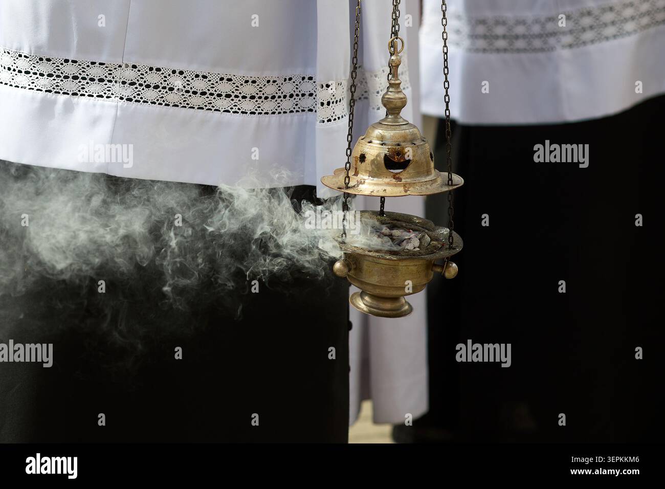 Priester hält ein Räuchergefäß und schwingt aromatischen Weihrauchdampf Stockfoto