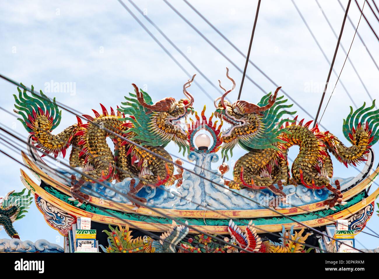 Eine lebendige, farbenfrohe Skulptur zweier mythologischer Drachenfiguren auf einem traditionellen Tempeldach, die komplexe Handwerkskunst, lebendige Details zeigt Stockfoto