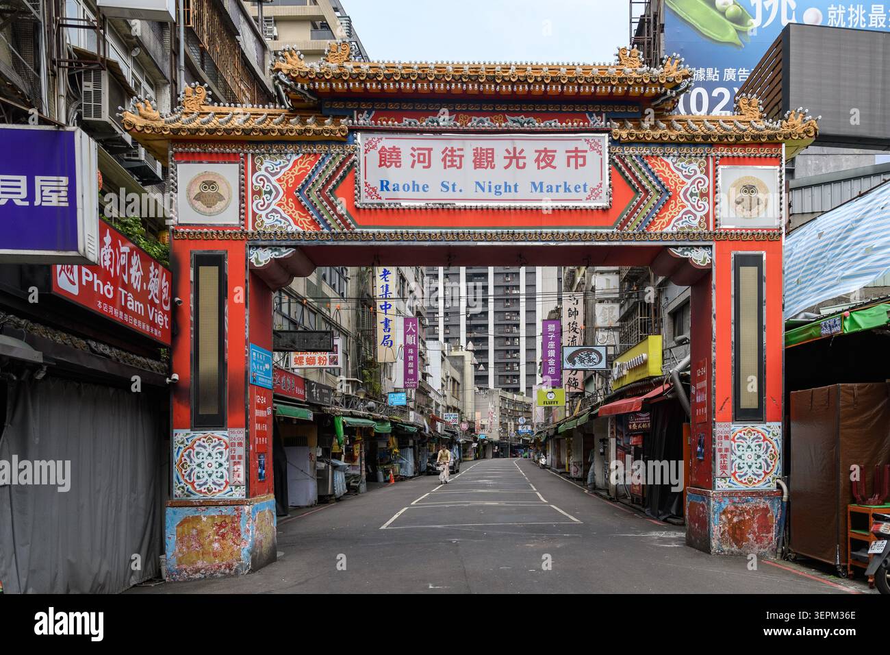 Taipei, Taiwan - 3. Mai 2026: Das kunstvoll verzierte Tor des Nachtmarktes in der Raohe Street umrahmt eine ruhige Straße mit farbenfrohen Schaufensterfassaden und spiegelt den Charme Taipes wider Stockfoto